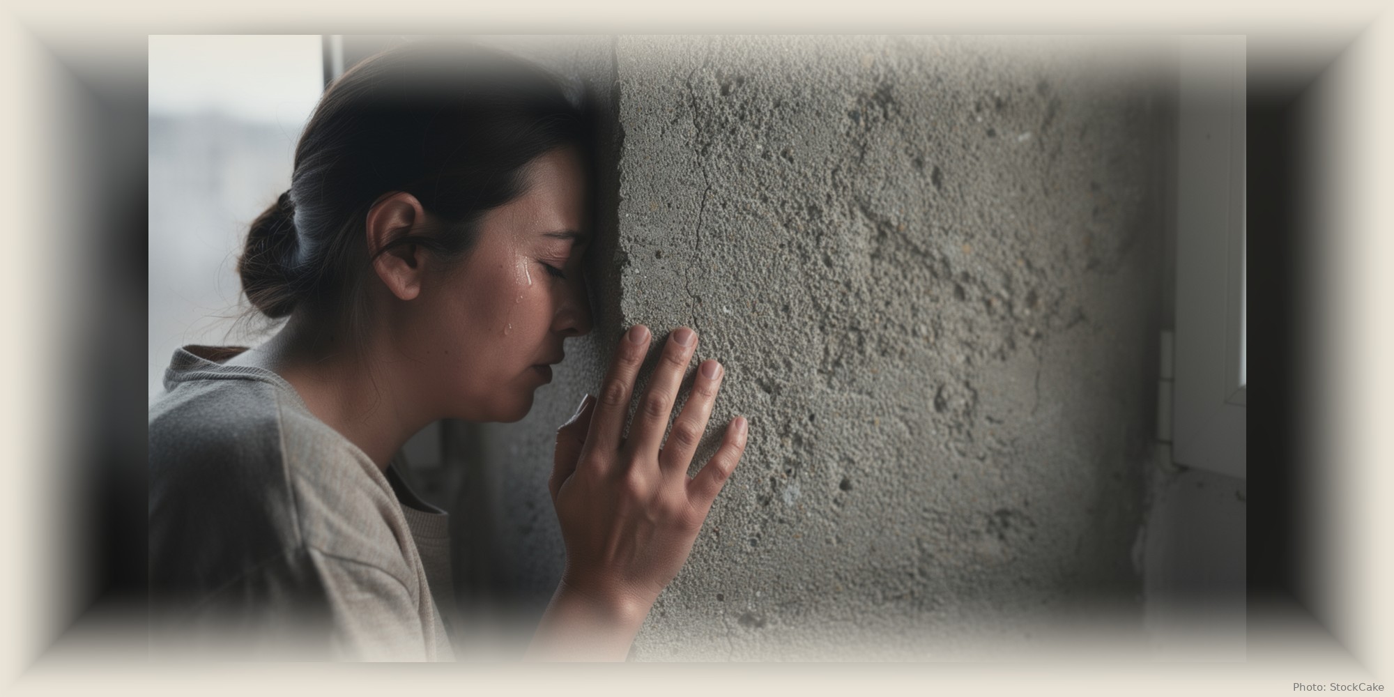 A woman sits against a bare concrete wall, carrying the weight of a hard decision.