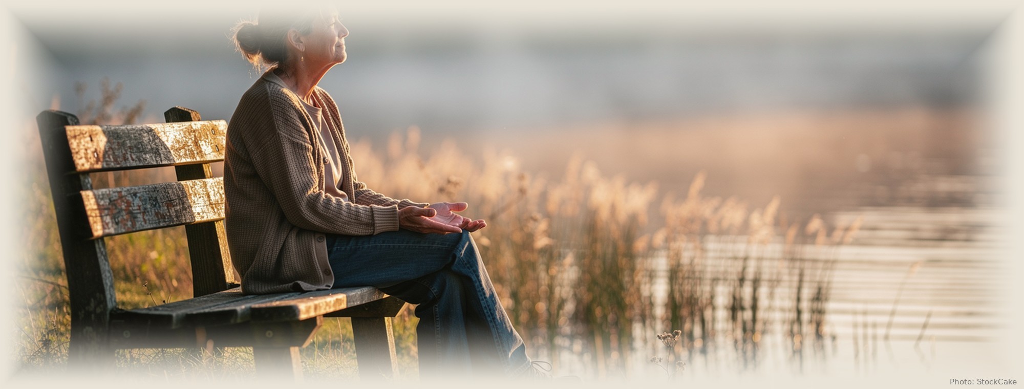 A calm lake at first light, a single figure resting in the stillness of a new morning.