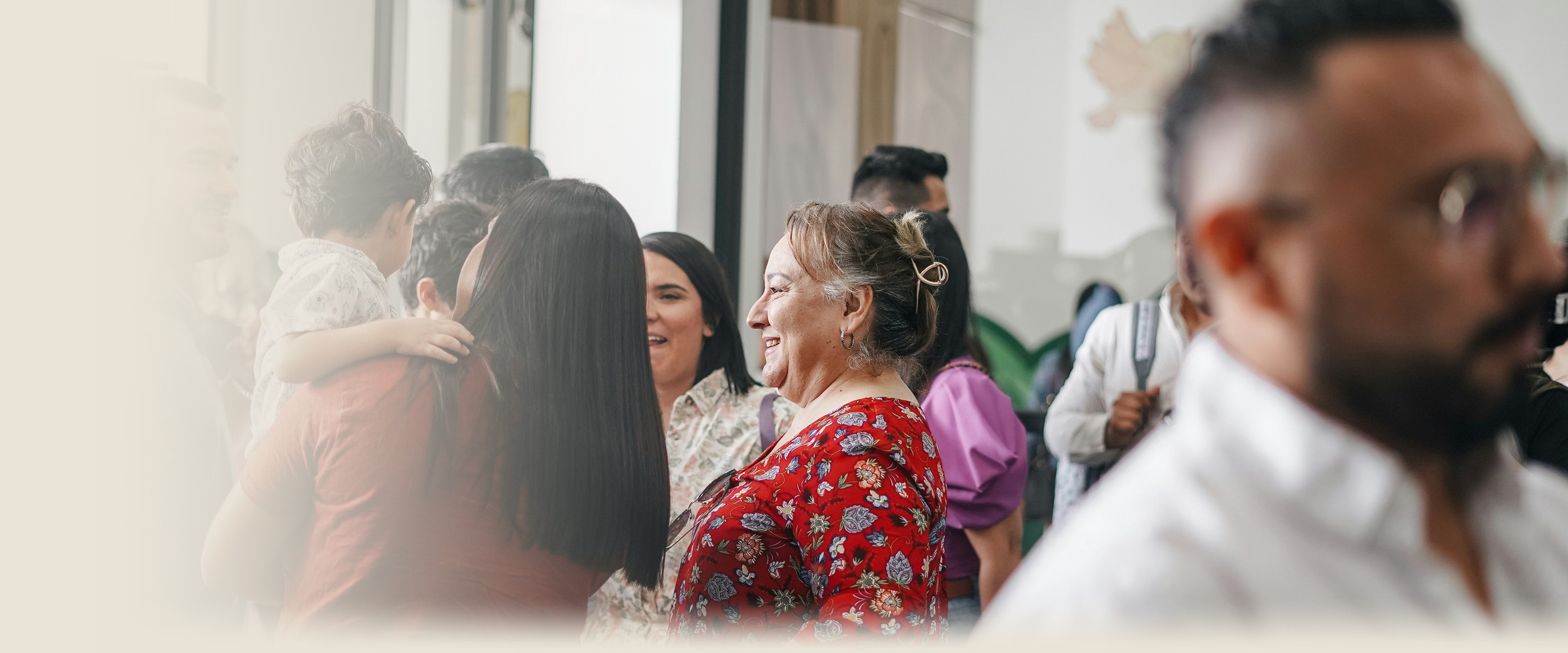 A group of people stand close together in conversation at a community gathering.