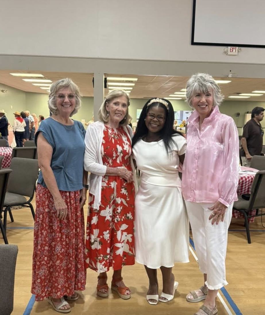 Four guests standing together in the hall, smiling.