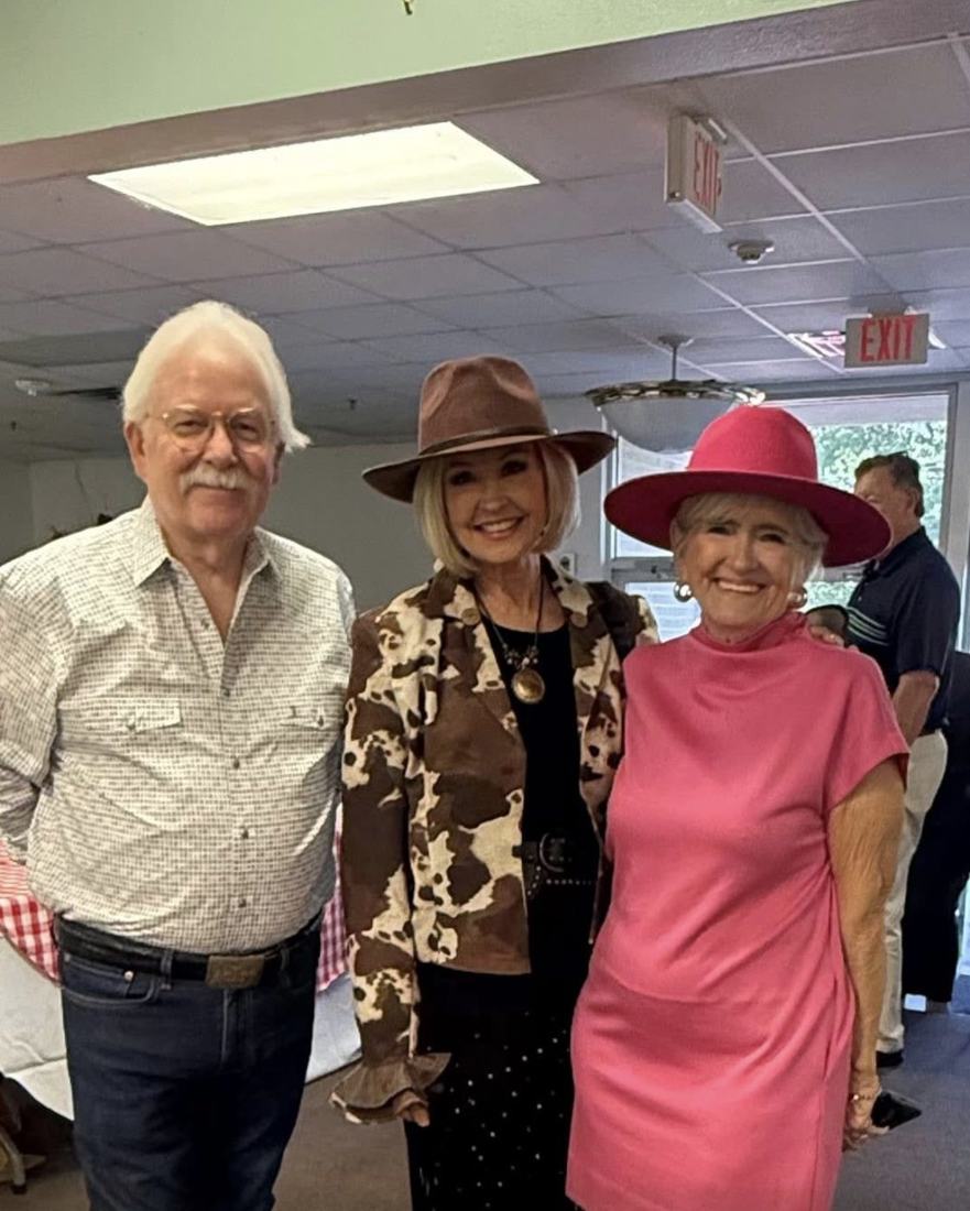 Three guests standing together, two of them wearing wide-brimmed hats.