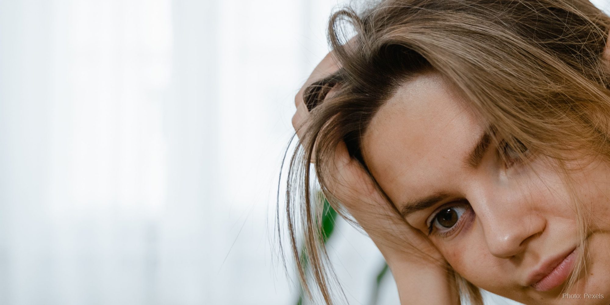 A woman pauses in a quiet, worried moment, hand resting in her hair, wishing to be truly seen and heard.